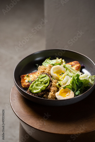 Plate with breakfast salads: avocado toast, egg, greens, fried cheese, quinoa
