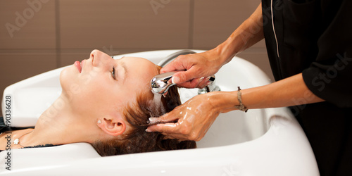 Hair stylist at work - hairdresser washing hair to the customer before doing hairstyle - banner size