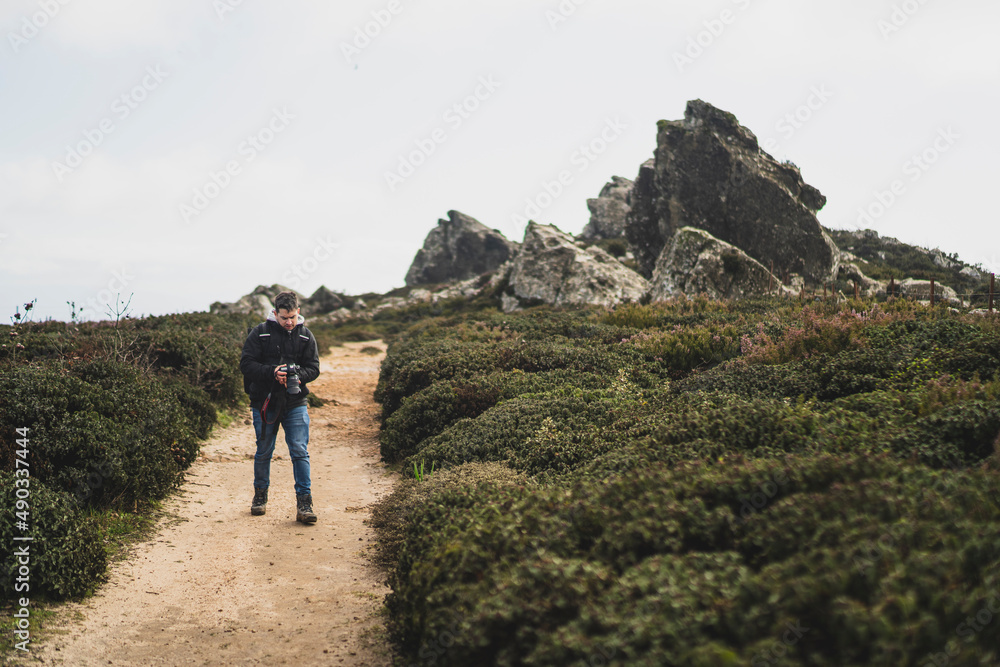 Chico joven  con cámara de fotos realizando senderismo por sierra andaluza