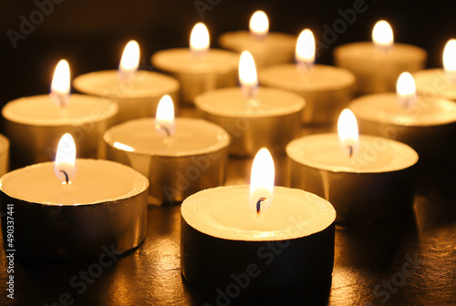 pointLots of candles on a wooden tablefocusspot specifically in on a black background.