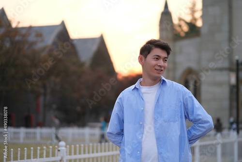 portrait of one handsome Asian young man in public park at sunset looking away