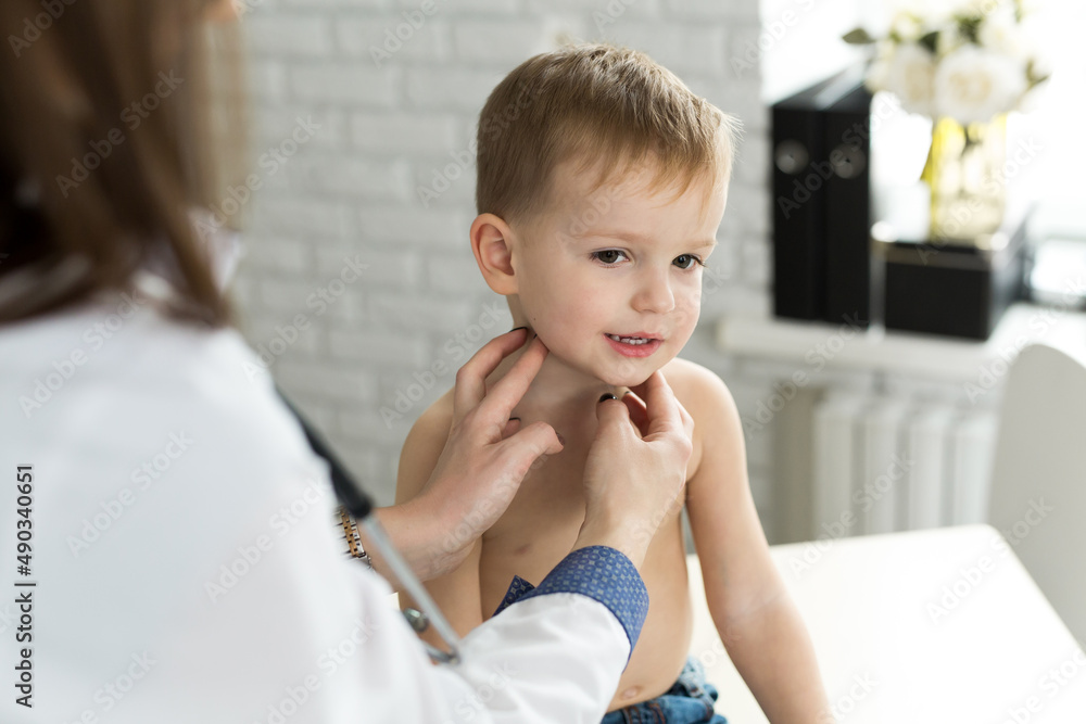 Pediatrician examining thyroid gland of little boy in clinic Pediatrician examining thyroid gland of little boy in clinic