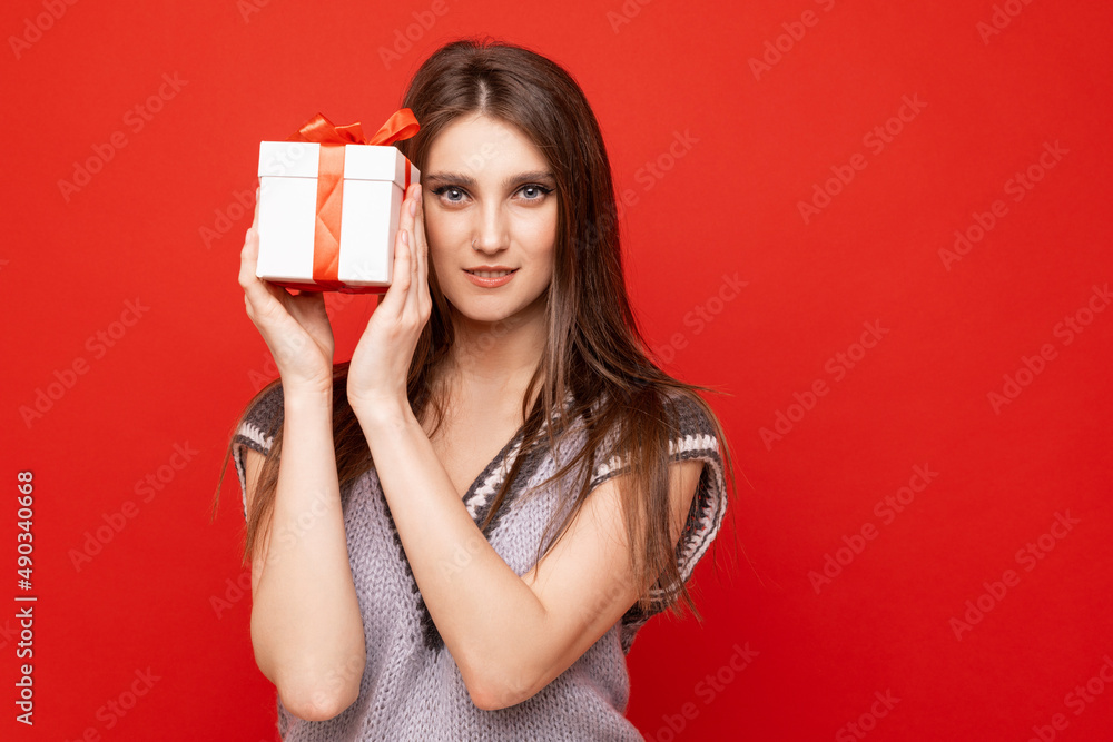 Portrait of a young woman with a gift box on a red background Portrait of a young woman with a gift box on a red background