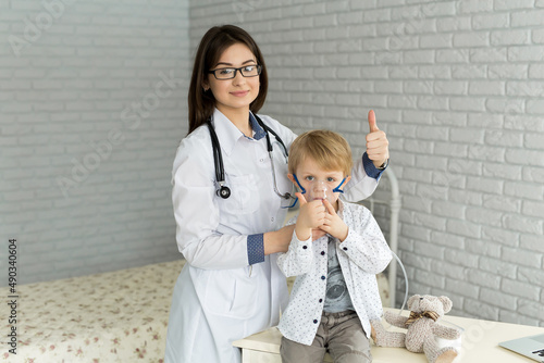 .Medical doctor applying medicine inhalation treatment on a little boy with asthma inhalation therapy by the mask of inhaler.