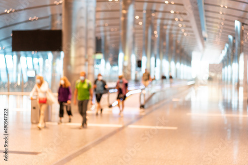 Abstract blurred passengers in an Asian airport background. Motion blur crowed of people walking along the hallway.