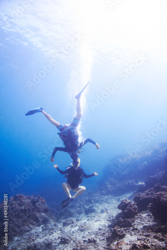 Underwater escapades. Two buoyant scuba divers fooling around underwater head to head and upside down - Copyspace.