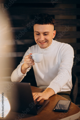 Man drinking coffee in a cfe and working on laptop photo