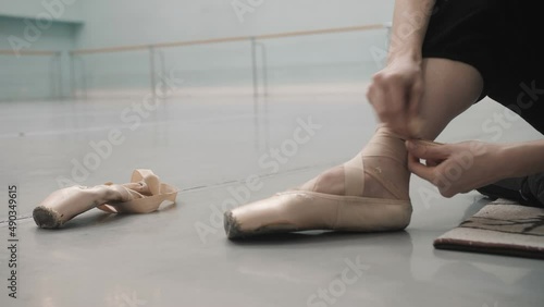 ballerina in the rehearsal room tying ballet flats. Preparing for rehearsal. close-up photo