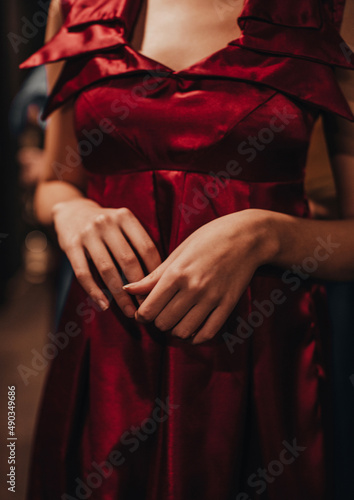 Female fashion figure in red classy silky dress on backstage. Vertical fashion shot