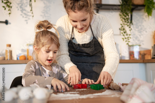 Young mother with preschool child girl making cookies in kitchen together, enjoying weekend at home. Caring mom teaching cute kid daughter to cook, preparing surprise for family.