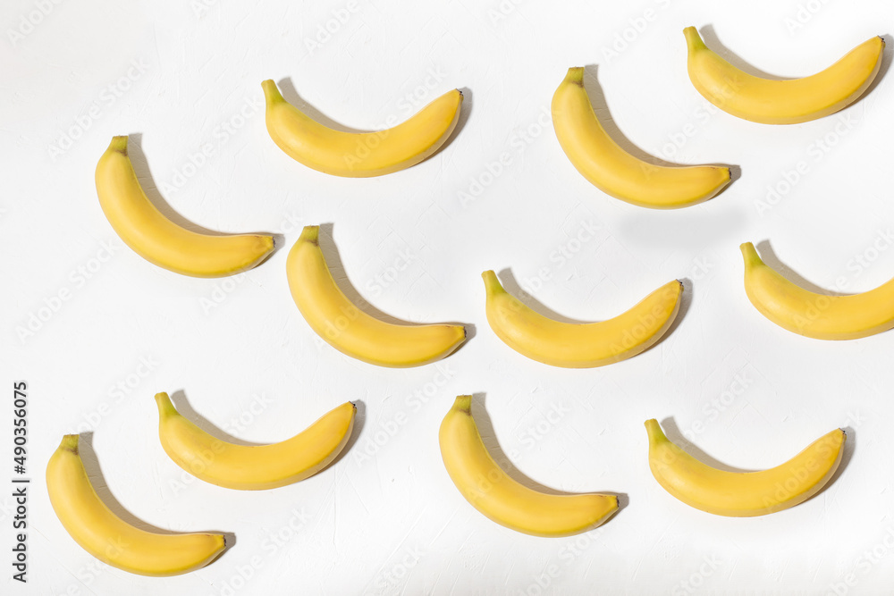 Background from bananas on a white background. View from above. Lots of yellow bananas. Minimalistic design.