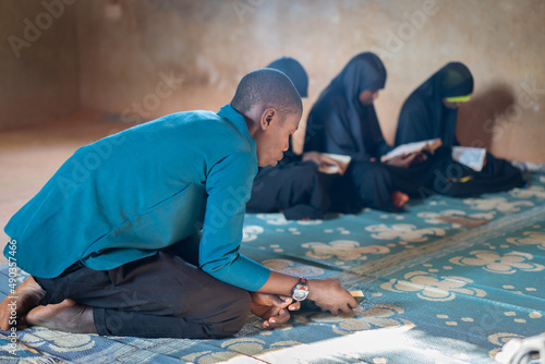 Canvas Print African teenage boys and girls sitting and reading book in poor school, high qua