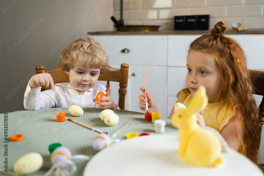 Brother and sister paint Easter eggs sitting at the kitchen table Brother and sister paint Easter eggs sitting at the kitchen table