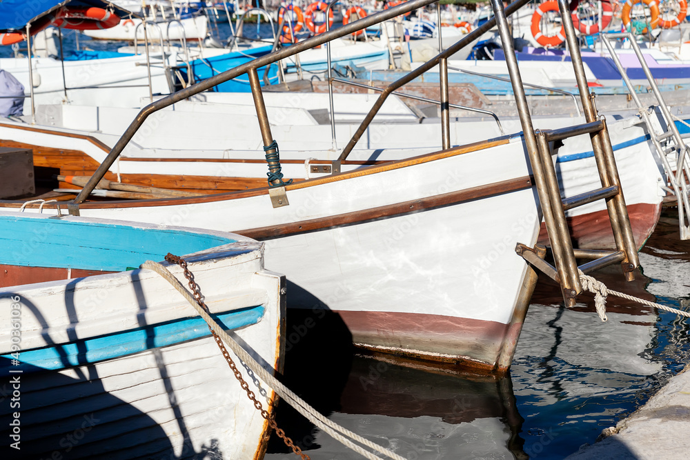 Row of many small old wooden vintage colorful bright fishing ships moored at fisherman village marina clear water bay on bright sunny day. Sea harbor with traditional retro vessels background