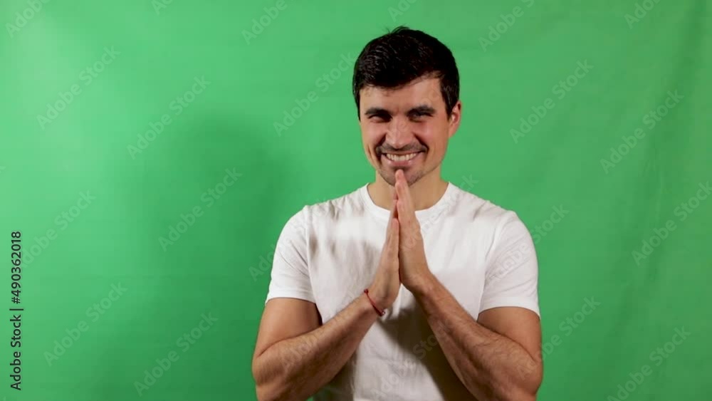 A handsome young man in a white shirt rubbing his hands with confidence and looks ahead with a smile on his face. Green screen A handsome young man in a white shirt rubbing his hands with confidence and looks ahead with a smile on his face. Green screen