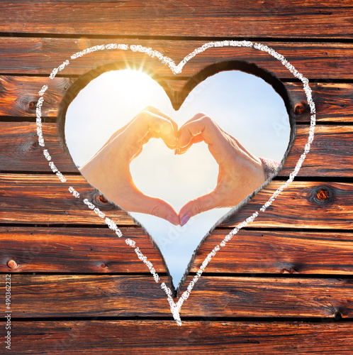 Handerz durch ein Herz in einer Holzwand gesehen