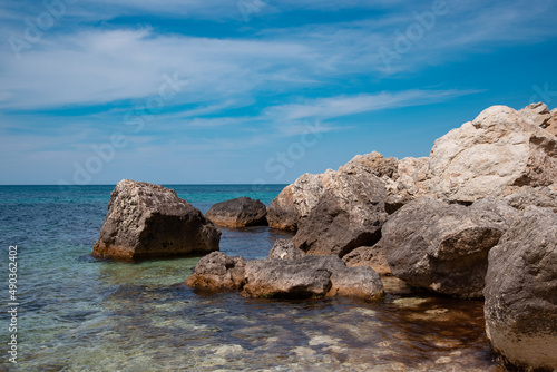 Summer seascape. Rocks and stones near the coastline. Blue sky and ocean.