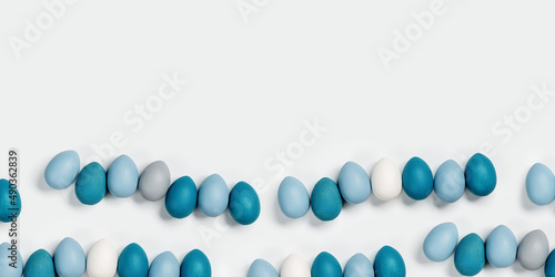 Dyed Easter eggs pastel colors blue, gray in row on white Happy Easter holiday wide banner, celebration food concept, chicken egg monochrome color. Top view table, copy space.