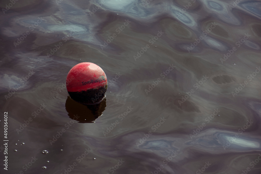 London, UK - September 17th 2021: a round red buoy drifting on the water