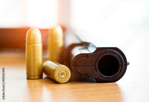 Gun with ammunition on wooden table