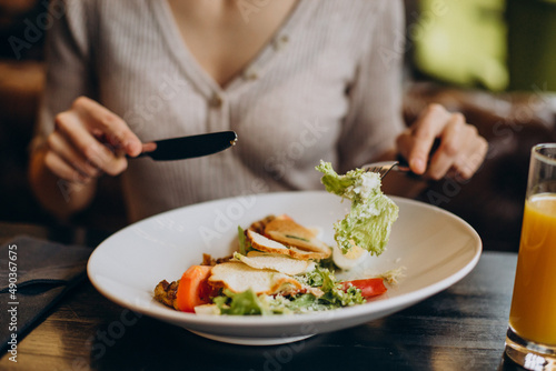 Young woman eating healthy breakfast with juice in a cafe close up