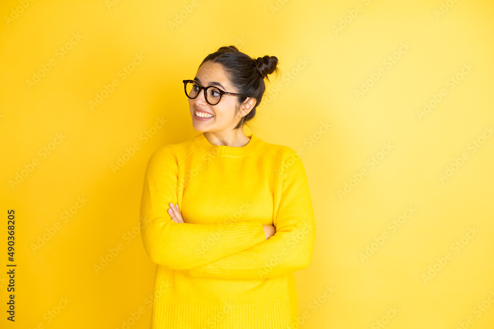 Young beautiful woman wearing casual sweater over isolated yellow background looking to side, relax profile pose with natural face and confident smile.