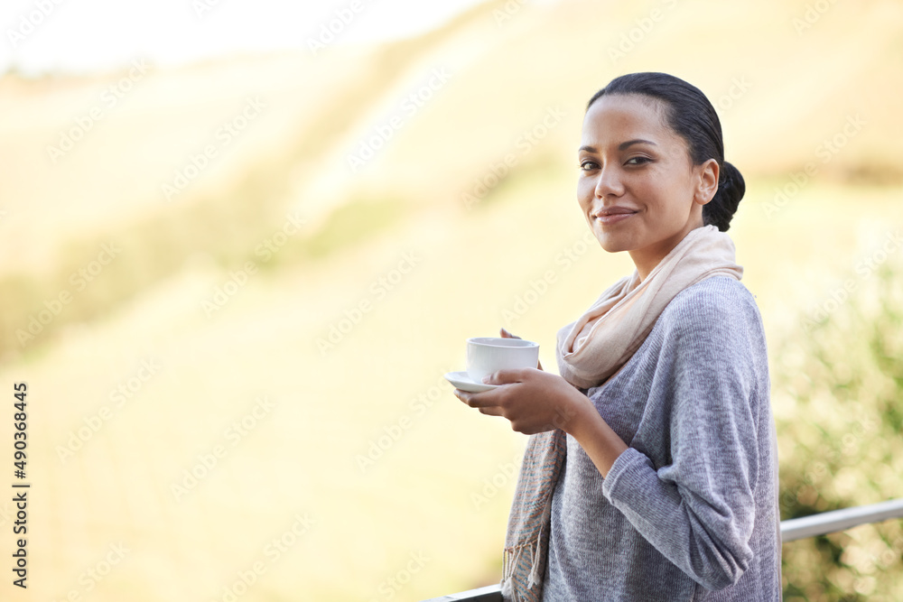 Relaxing with her favorite drink. Shot of a a young ethnic girl enjoying a cup of coffee outside.