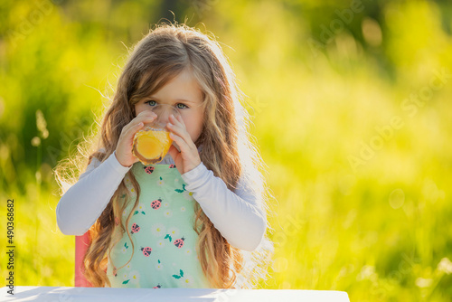 child drinking orange juice while outdoors