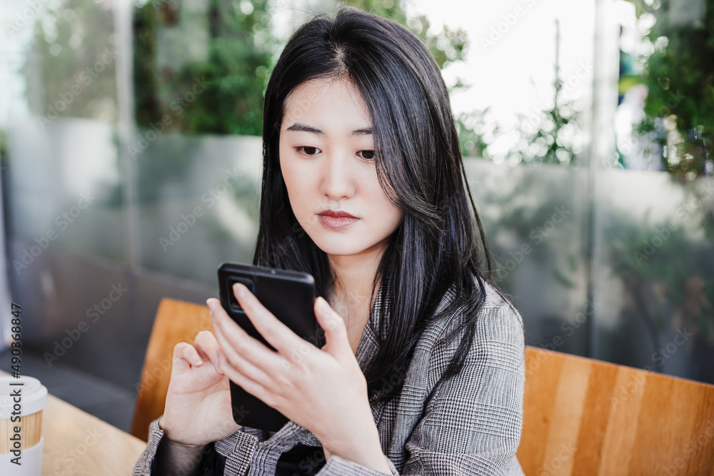 professional chinese entrepreneur woman working on mobile phone in cafeteria. Technology, lifestyle professional chinese entrepreneur woman working on mobile phone in cafeteria. Technology, lifestyle