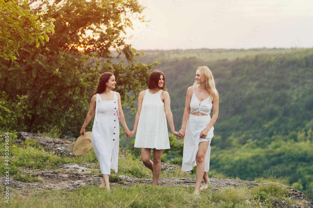 Company of three young female friends having fun, enjoy green hill landscape and beautiful sunset at summer picnic. Company of three young female friends having fun, enjoy green hill landscape and beautiful sunset at summer picnic.