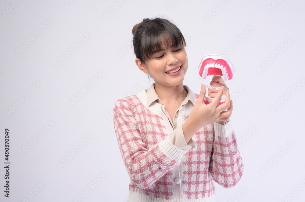 Young smiling woman holding invisalign braces over white background studio, dental healthcare and Orthodontic concept. Young smiling woman holding invisalign braces over white background studio, dental healthcare and Orthodontic concept.