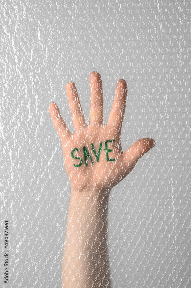 Social activism. The inscription Save is written on the palm of a human hand behind a transparent plastic bubble wrap. Save Planet concept. Male hand showing stop sign Social activism. The inscription Save is written on the palm of a human hand behind a transparent plastic bubble wrap. Save Planet concept. Male hand showing stop sign