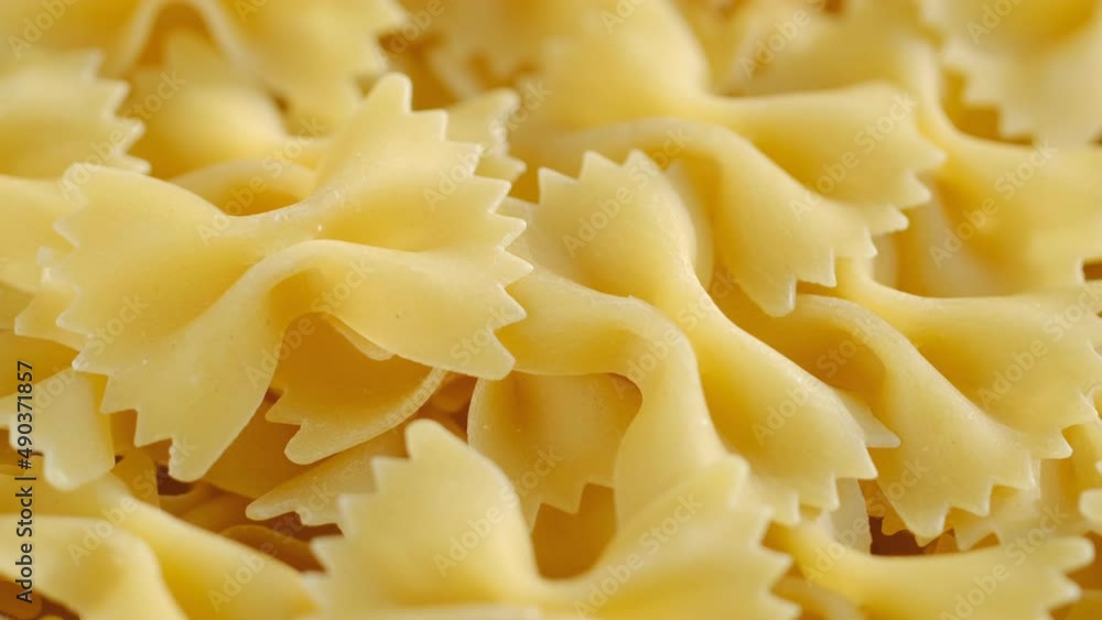 Farfalle, bow tie shaped dry pasta in rotation.Studio shot. Close Up, background.Stack of Dry uncooked farfalle Farfalle, bow tie shaped dry pasta in rotation.Studio shot. Close Up, background.Stack of Dry uncooked farfalle