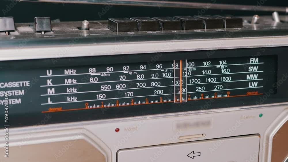 Tuning the Frequency, Searching Wave on an Old Vintage Analog Radio. Search for a music radio station on a dial scale on panel of a short-wave portable FM receiver, player, tape recorder 80s, 90s. Tuning the Frequency, Searching Wave on an Old Vintage Analog Radio. Search for a music radio station on a dial scale on panel of a short-wave portable FM receiver, player, tape recorder 80s, 90s.