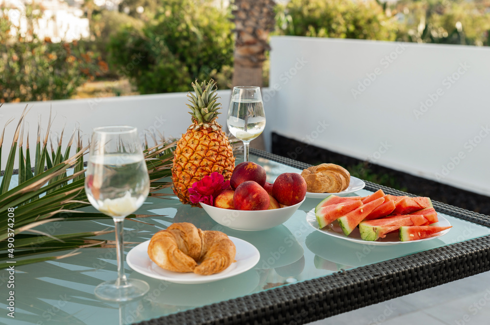 Tasty breakfast on glass table juice fruits with palm on background Tasty breakfast on glass table juice fruits with palm on background