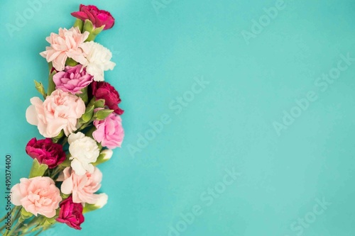 Fototapeta Naklejka Na Ścianę i Meble -  Bunch of carnations on turquoise flat lay with copy space