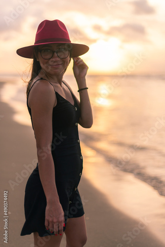 Young attractive latin girl with a red hat teasing at sunset photo