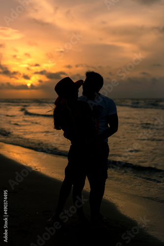 Young latin couple kissing each other on the beach at sunset