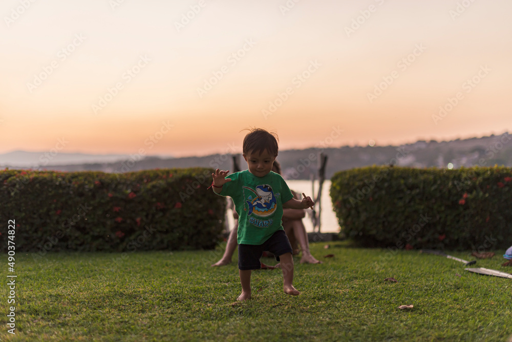 Cute toddler learning to walk on the garden at dusk