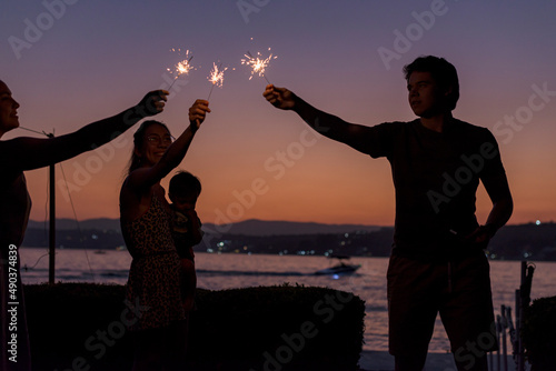 Silhouette of group of friends having with bengal lights at dusk photo