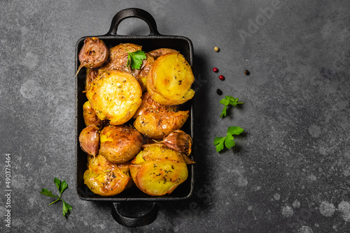 Fotografi Crispy smashed roast potatoes in cast iron skillet on dark background