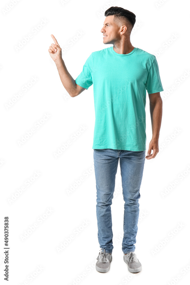 Handsome young man in stylish t-shirt pointing at something on white background Handsome young man in stylish t-shirt pointing at something on white background