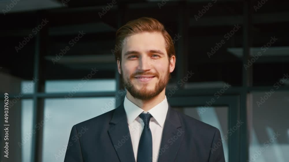 Young businessman smiling and looking at camera. Young man in a suit in the office Young businessman smiling and looking at camera. Young man in a suit in the office