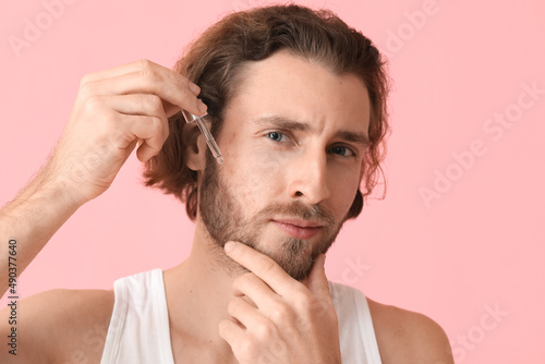Young man using serum for s...
