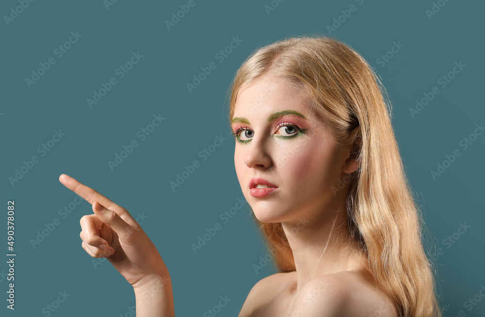 Beautiful girl with unusual eyebrows pointing at something on color background Beautiful girl with unusual eyebrows pointing at something on color background