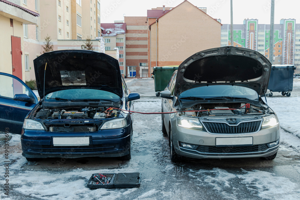 Charging a car battery in winter. Help on the road. Closeup. Connecting high voltage wires to