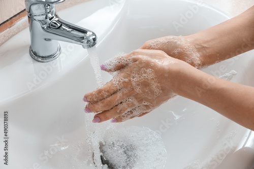 Woman washing her hands with foam in ceramic sink, closeup