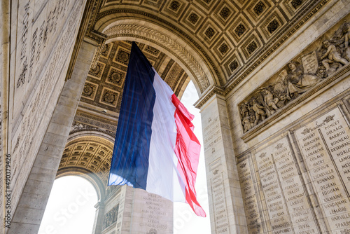 A large french flag fluttering under the Arc de Triomphe in Paris, France. © olrat