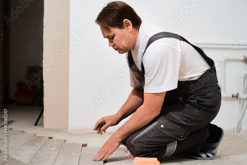 Construction worker installing ceramic floor over concrete floor using tile levelers, trowels and tile mortar. Laying floor ceramic tile. Renovating the floor. Close up, selective focus