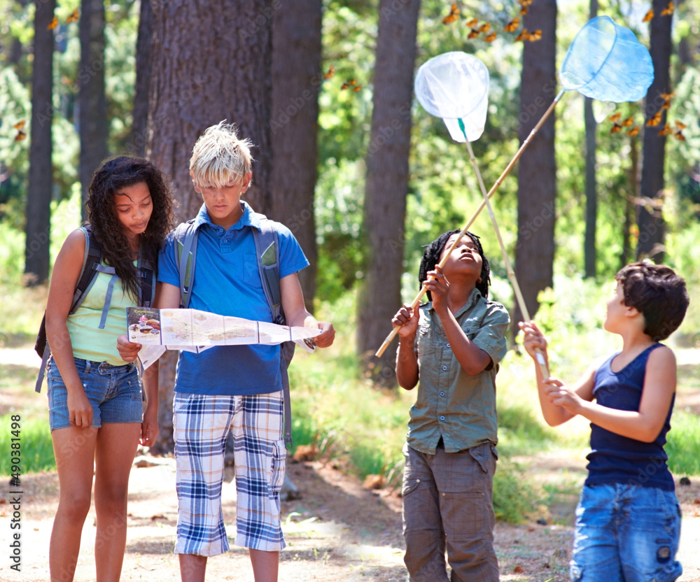 Fototapeta premium An outdoor experience. Multi-ethnic kids exploring a map while standing outside in a forest.